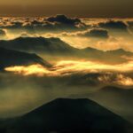 a sunset over a body of water with a mountain in the background