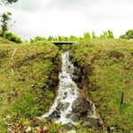 a waterfall surrounded by green grass and trees