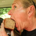a close up of a man eating a sandwich